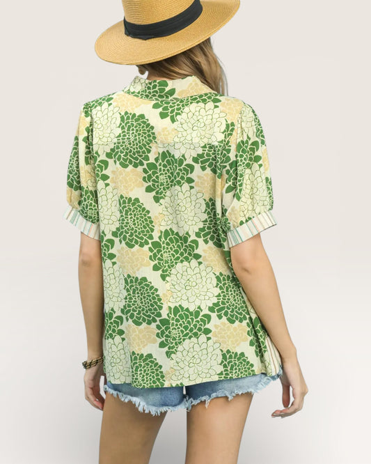 Person wearing a green floral patterned shirt and straw hat on a plain background