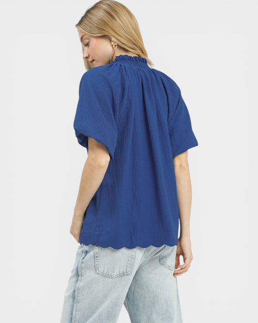 Woman wearing a blue blouse and light blue jeans on a white background