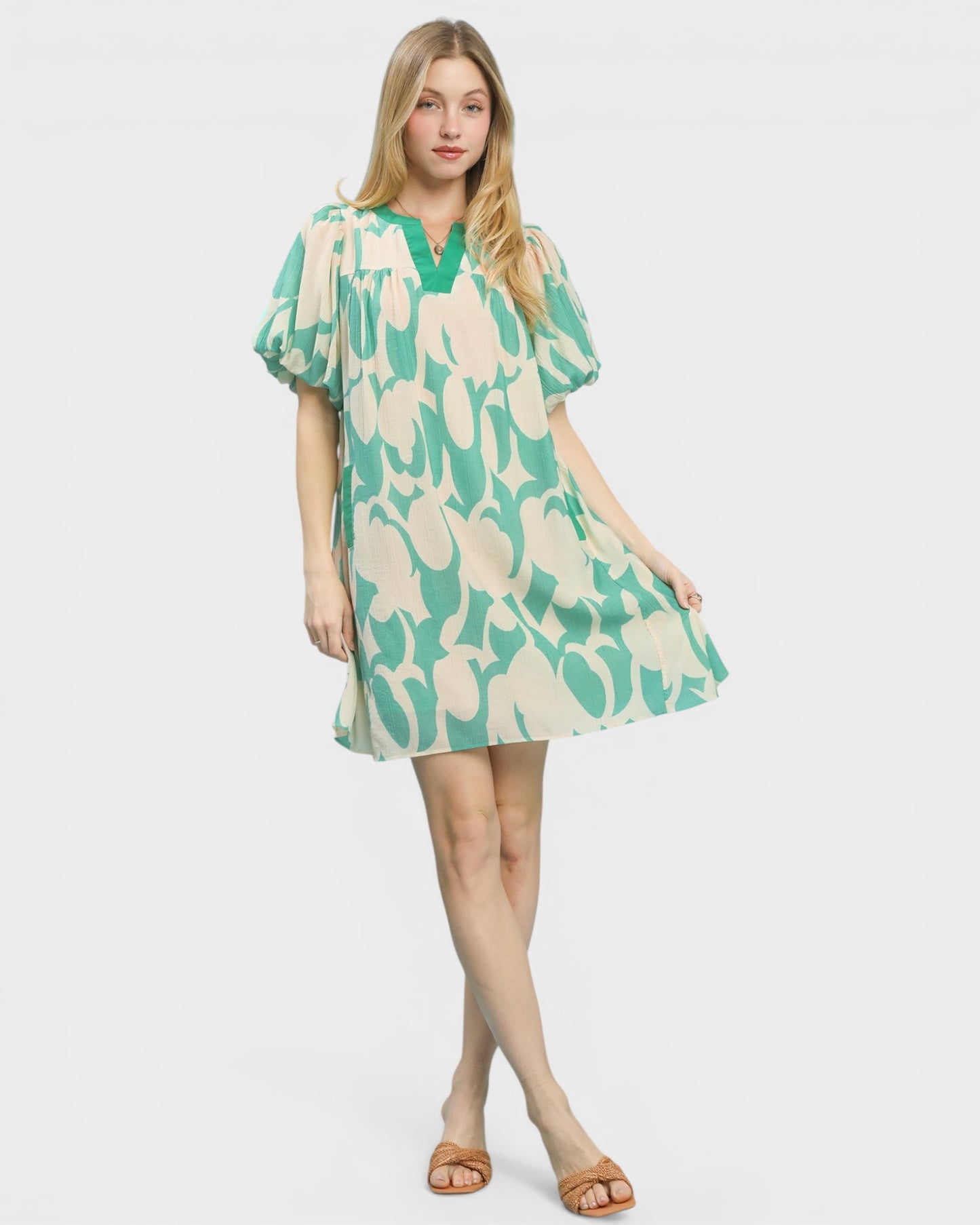 Woman wearing a green and beige patterned dress on a white background