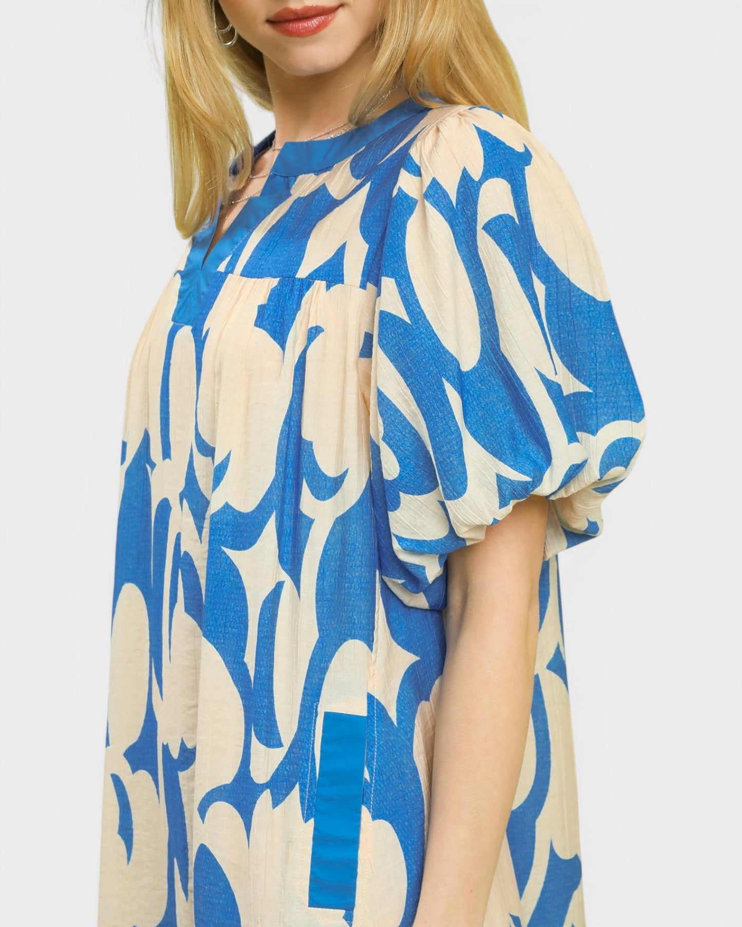 Woman wearing a blue and beige patterned dress on a plain background