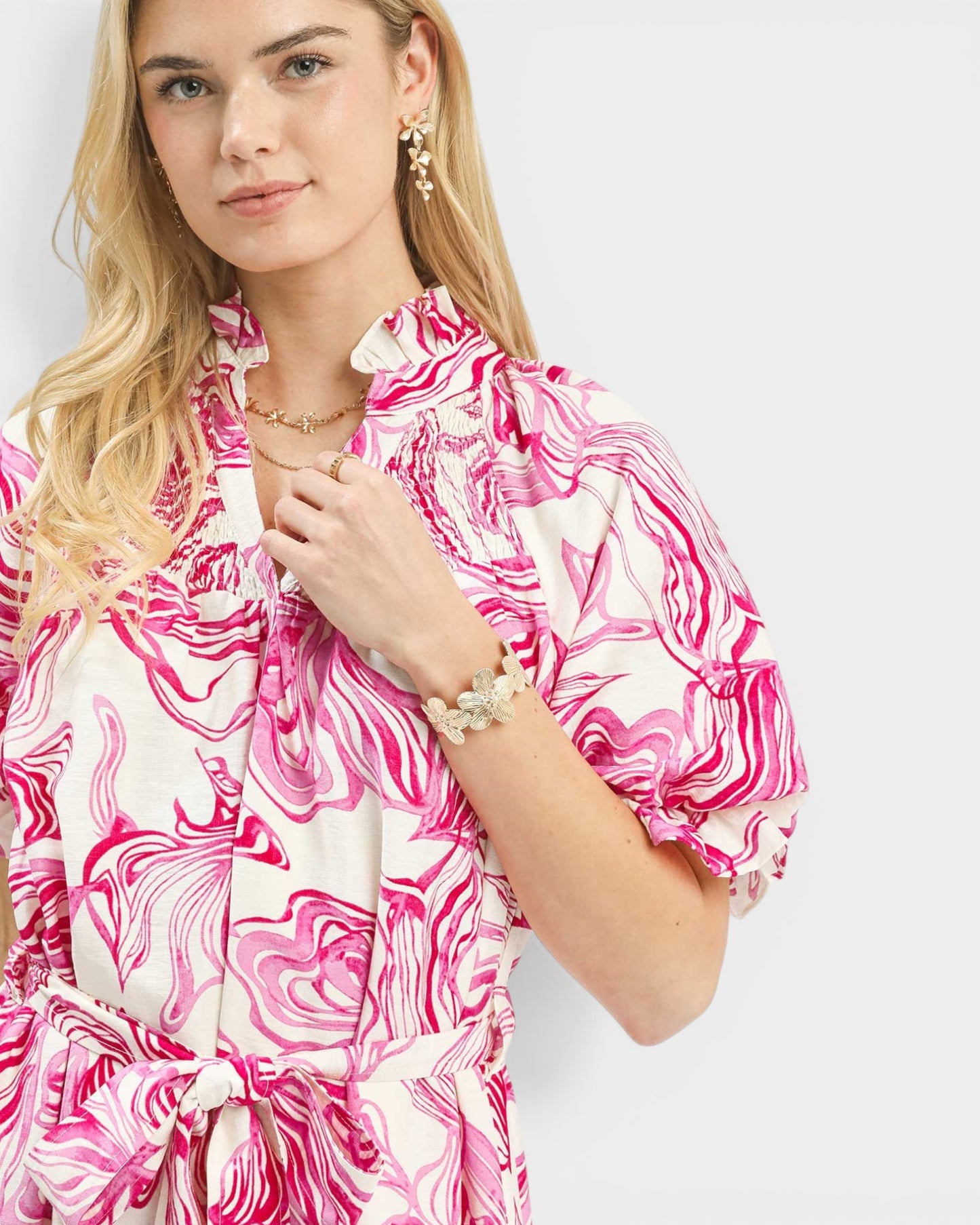 Woman wearing a pink and white patterned dress on a plain background