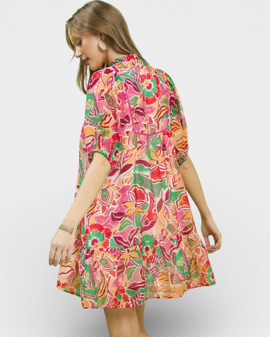 Woman wearing a colorful floral dress on a plain background