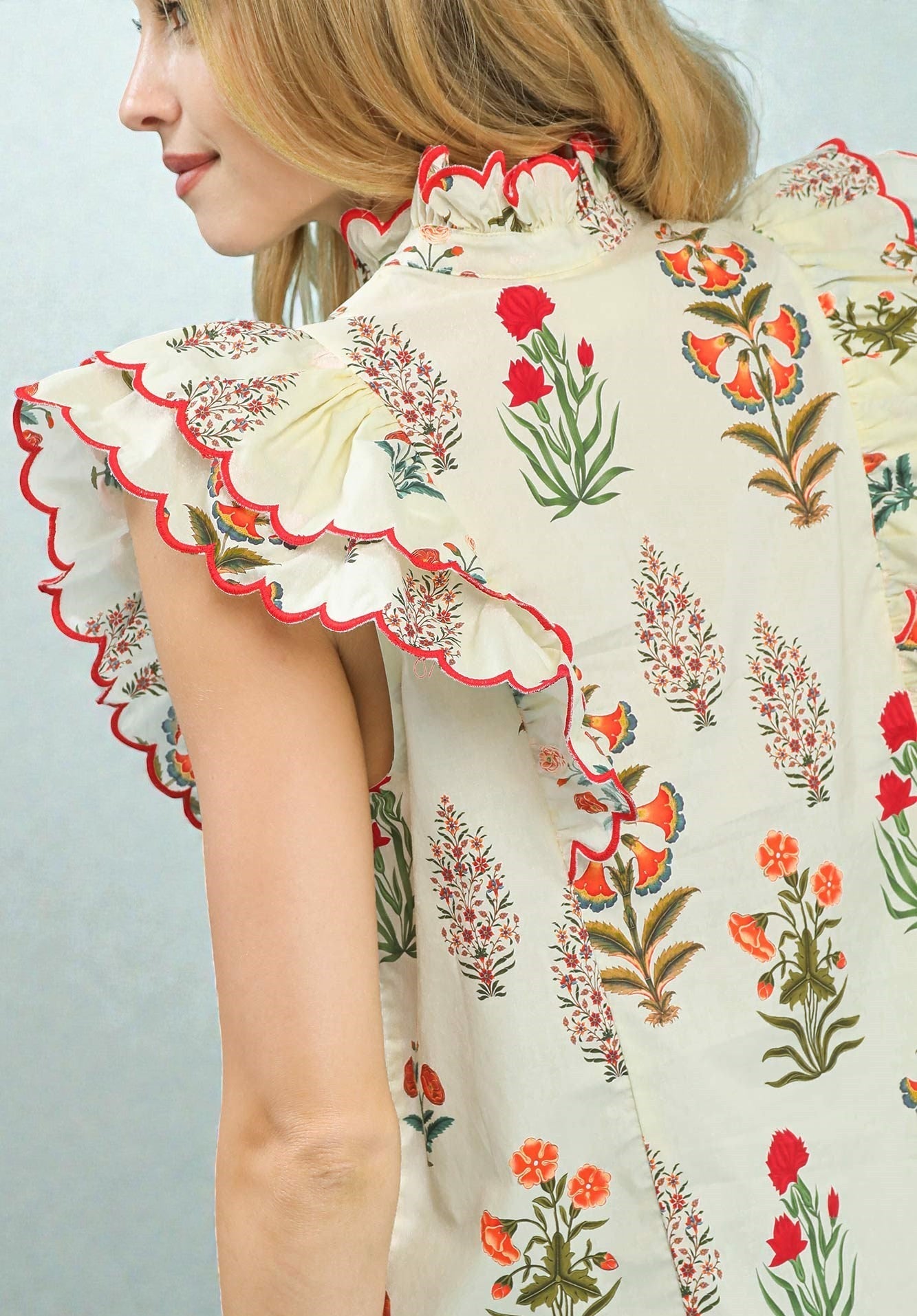 Woman wearing a floral dress with ruffled sleeves against a light background