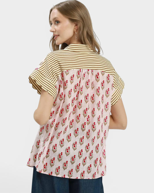 Woman wearing a shirt with a striped pattern on the front and a floral pattern on the back against a white background