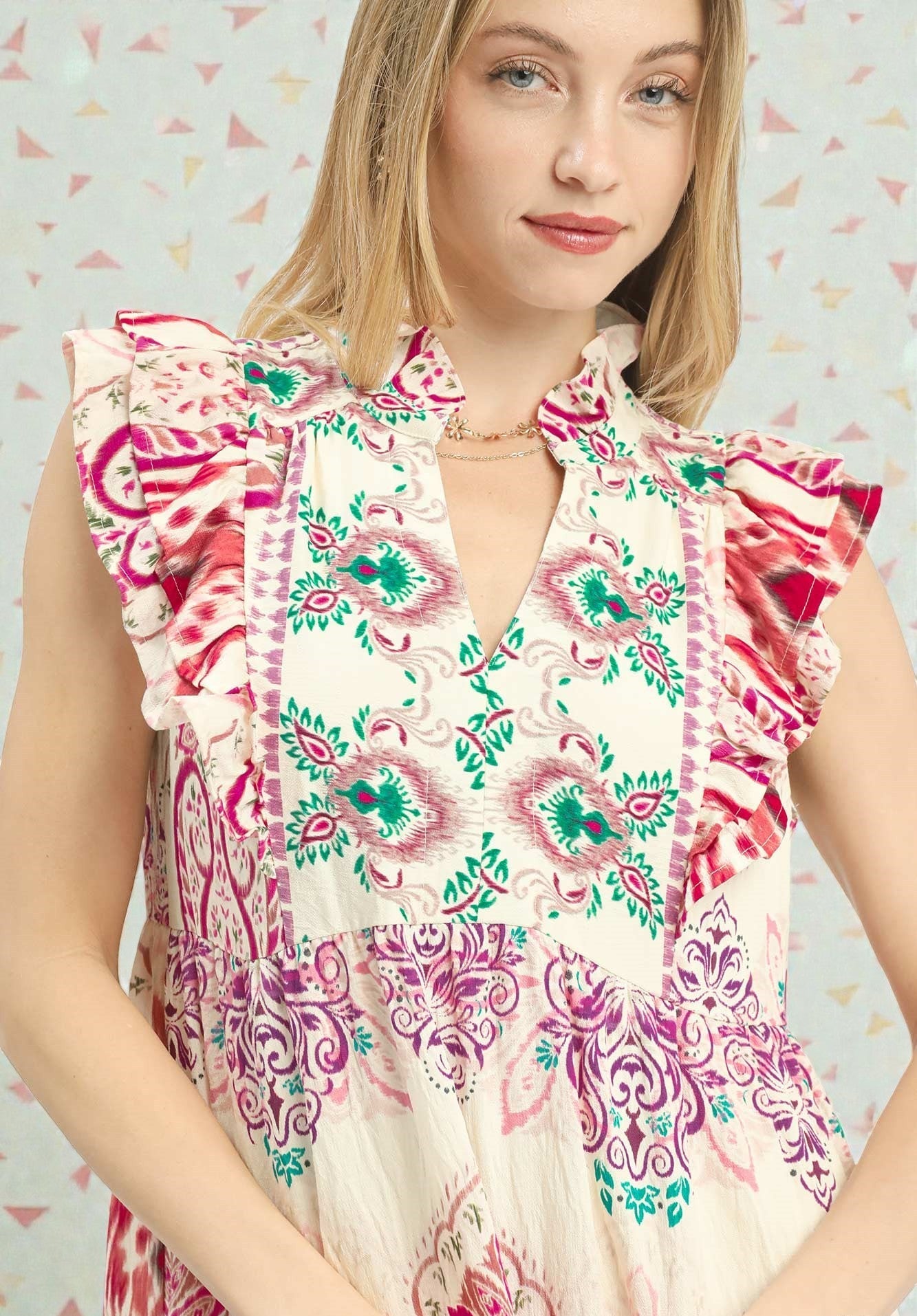 Woman wearing a floral dress with ruffled sleeves against a patterned background