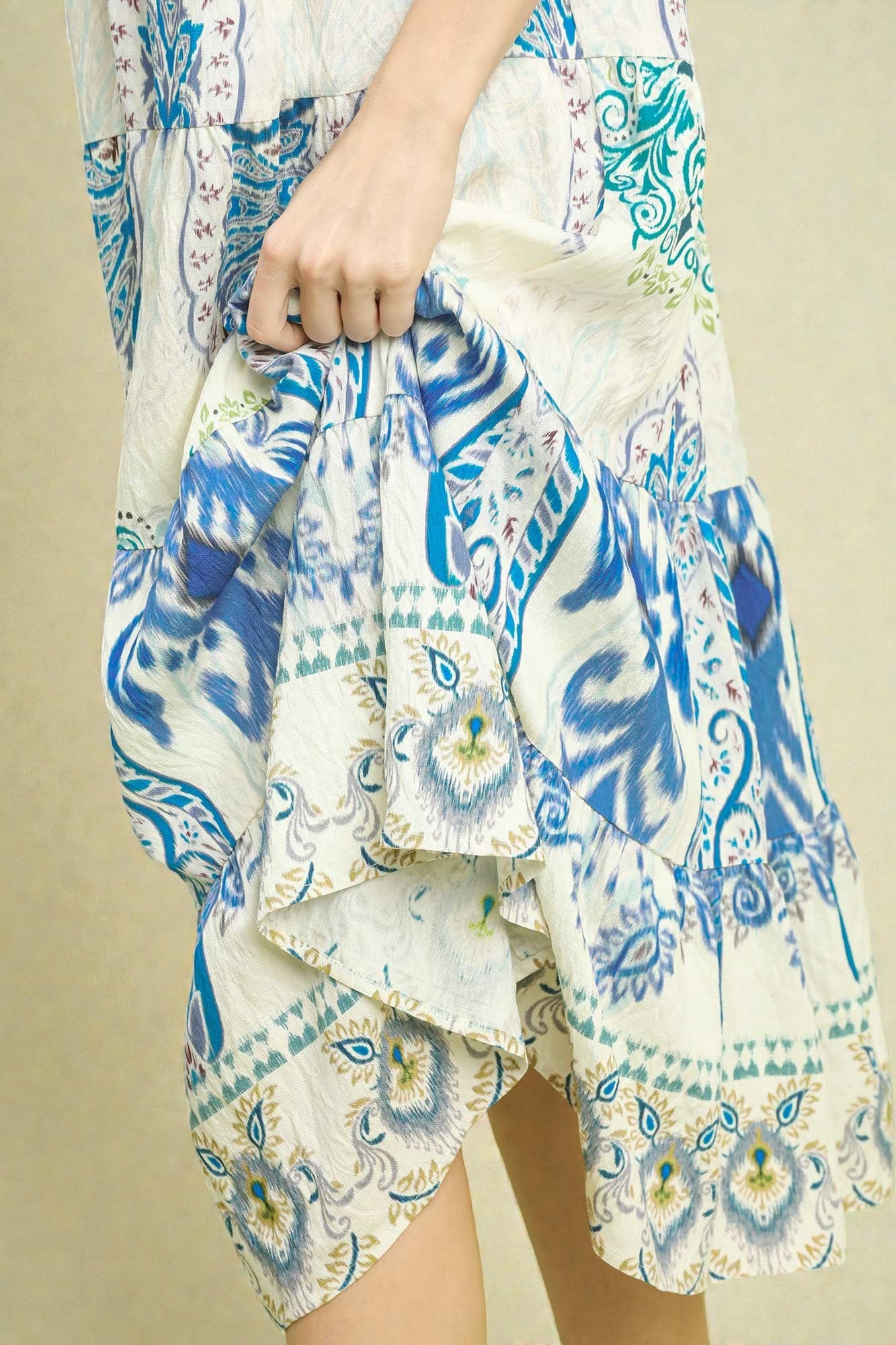 Person wearing a patterned outfit with blue and white design on a beige background