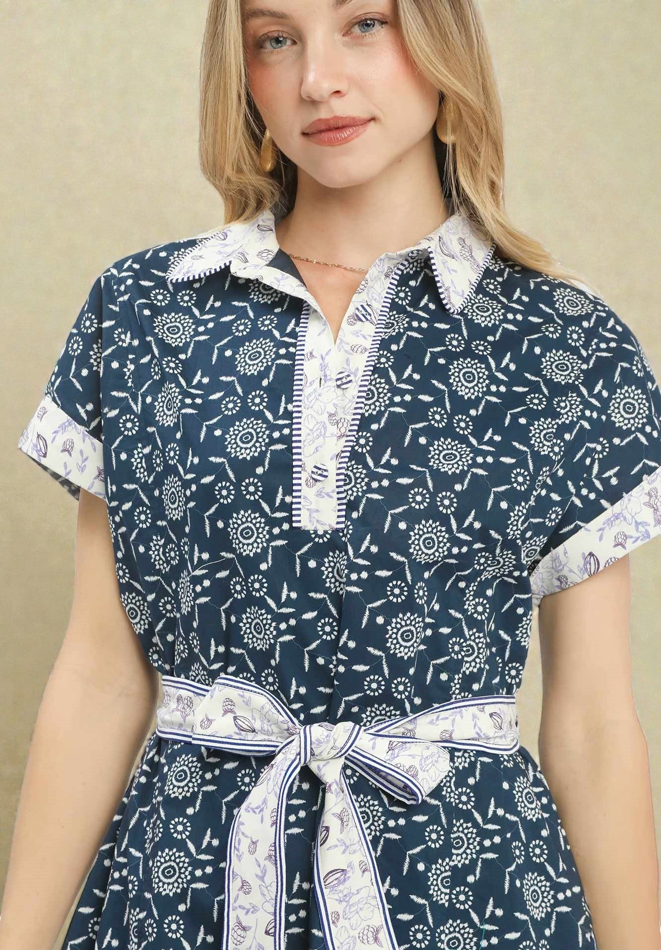 Woman wearing a navy dress with white floral pattern and white collar