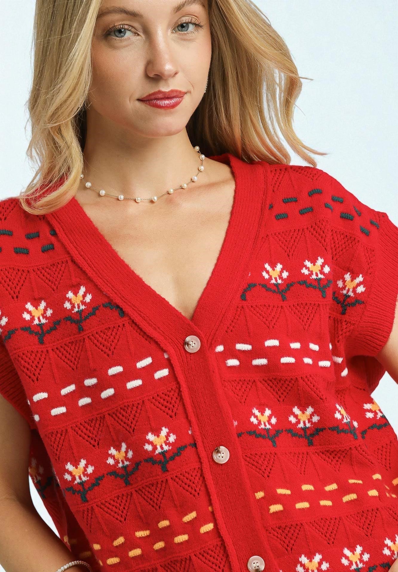 Woman wearing a red knitted cardigan with a pattern on a white background