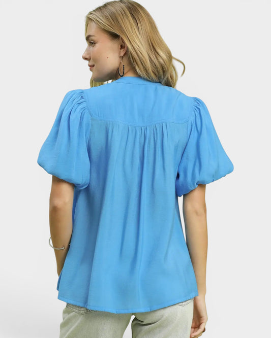 Woman wearing a blue blouse with puffed sleeves on a white background
