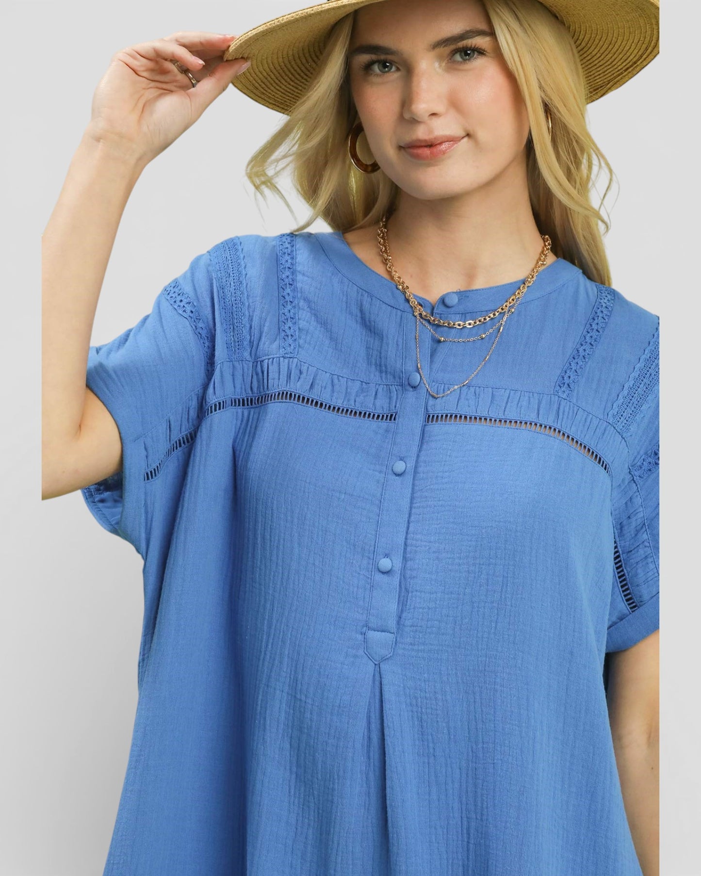 Woman wearing a blue dress and straw hat against a plain background