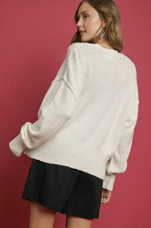 Person wearing a white sweater and black skirt against a red background