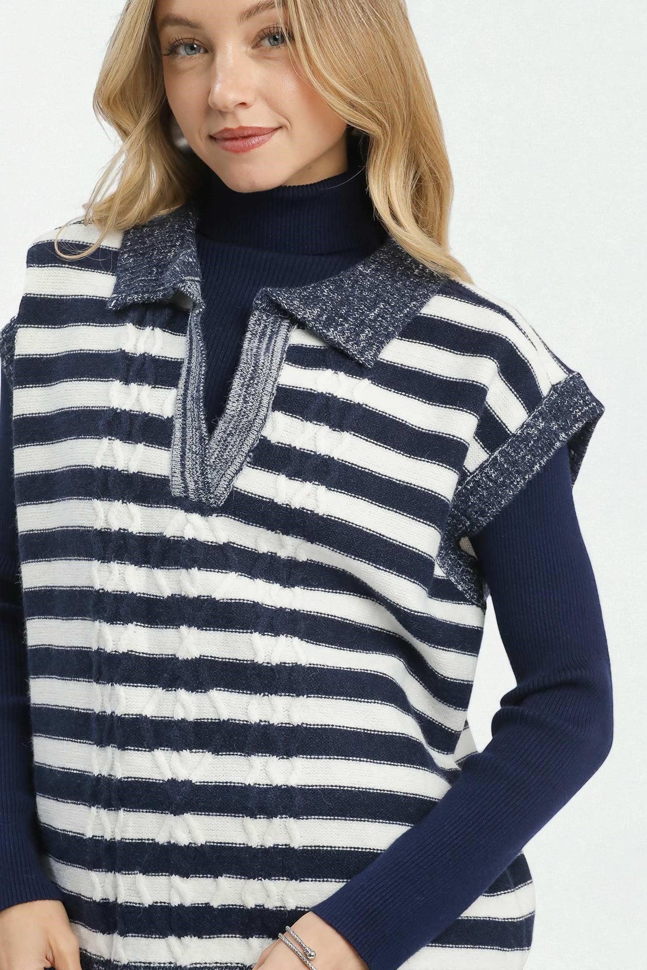 Woman wearing a navy and white striped vest over a dark blue long-sleeve shirt on a white background