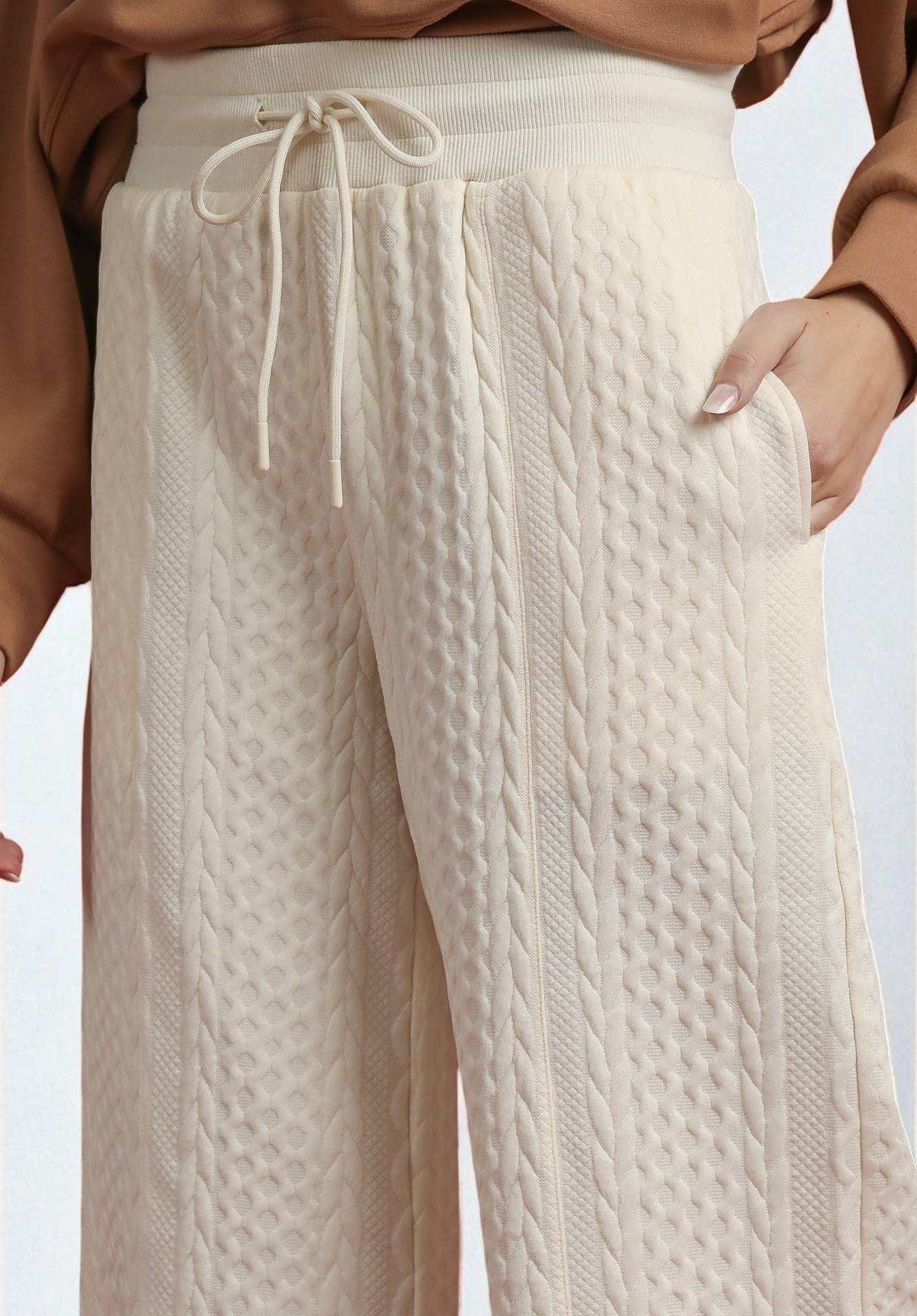 Beige textured pants with a drawstring waist on a light background