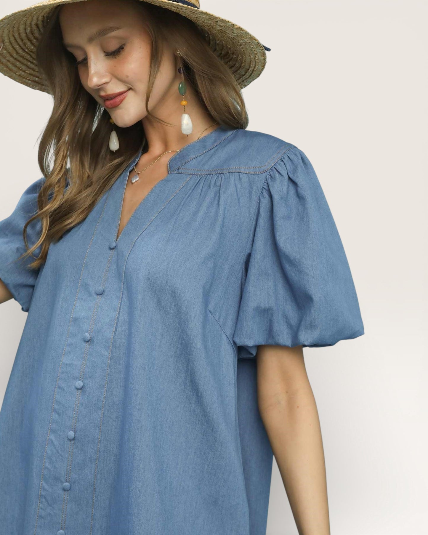 Woman wearing a blue dress and straw hat on a plain background