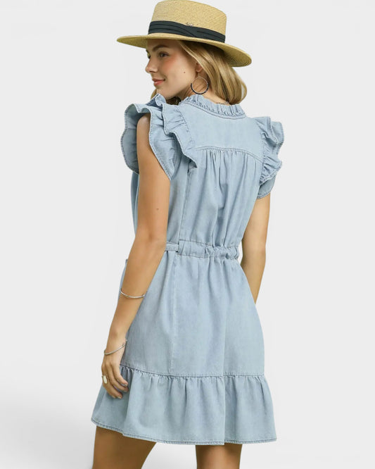 Woman wearing a light blue dress with ruffled details and a straw hat on a white background