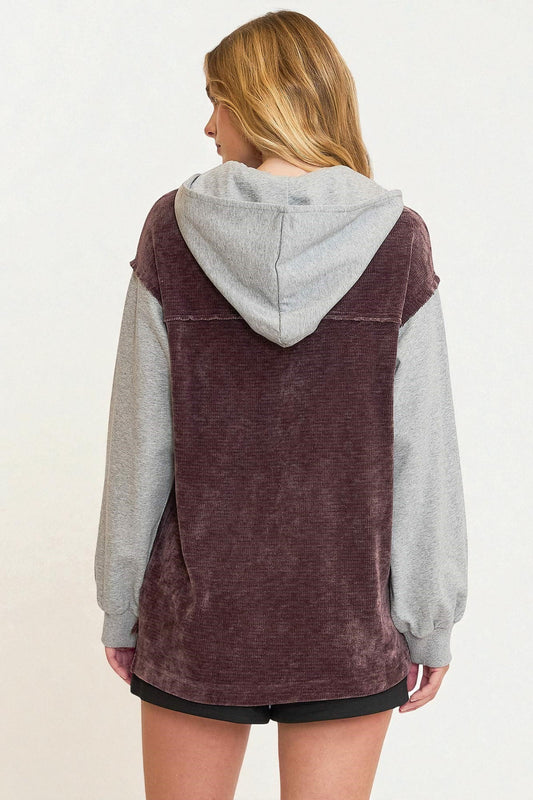 Person wearing a maroon and gray hoodie on a white background