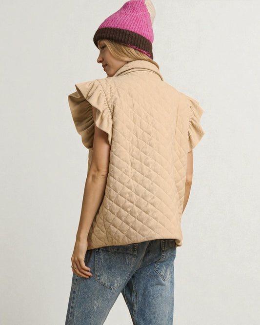 Person wearing a beige quilted vest, blue jeans, and a pink knit beanie on a light gray background