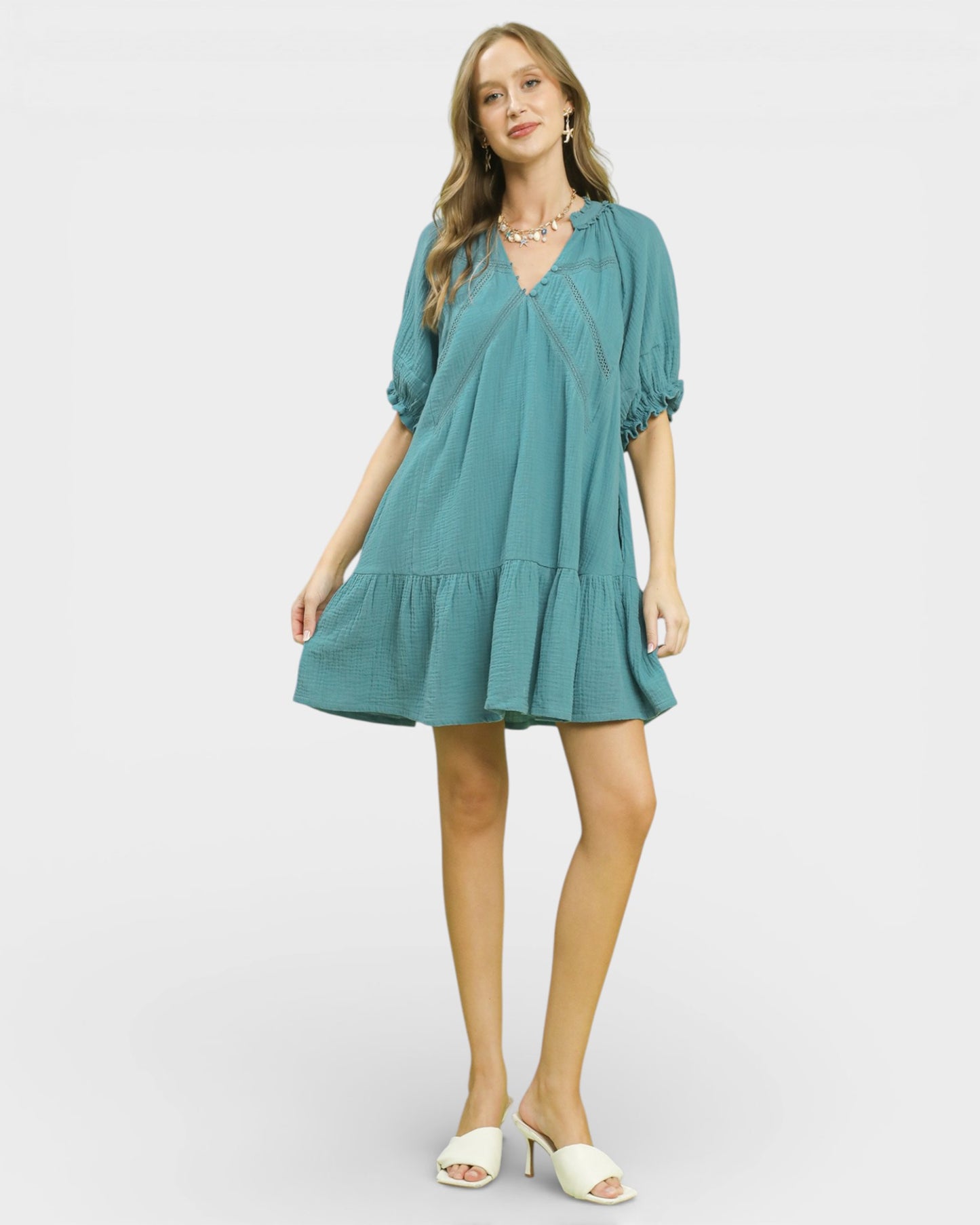Woman wearing a teal dress on a white background
