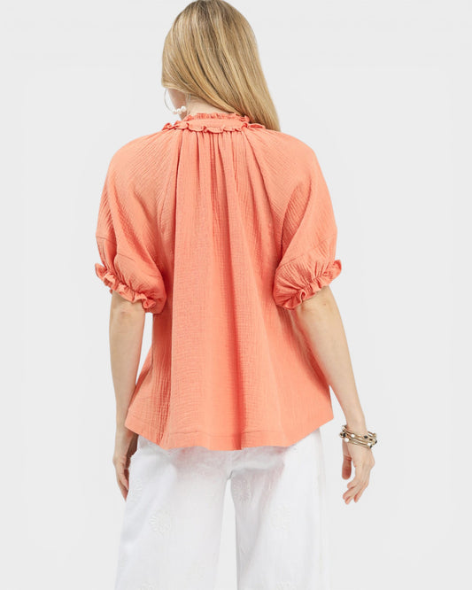 Woman wearing a coral blouse with puff sleeves on a white background