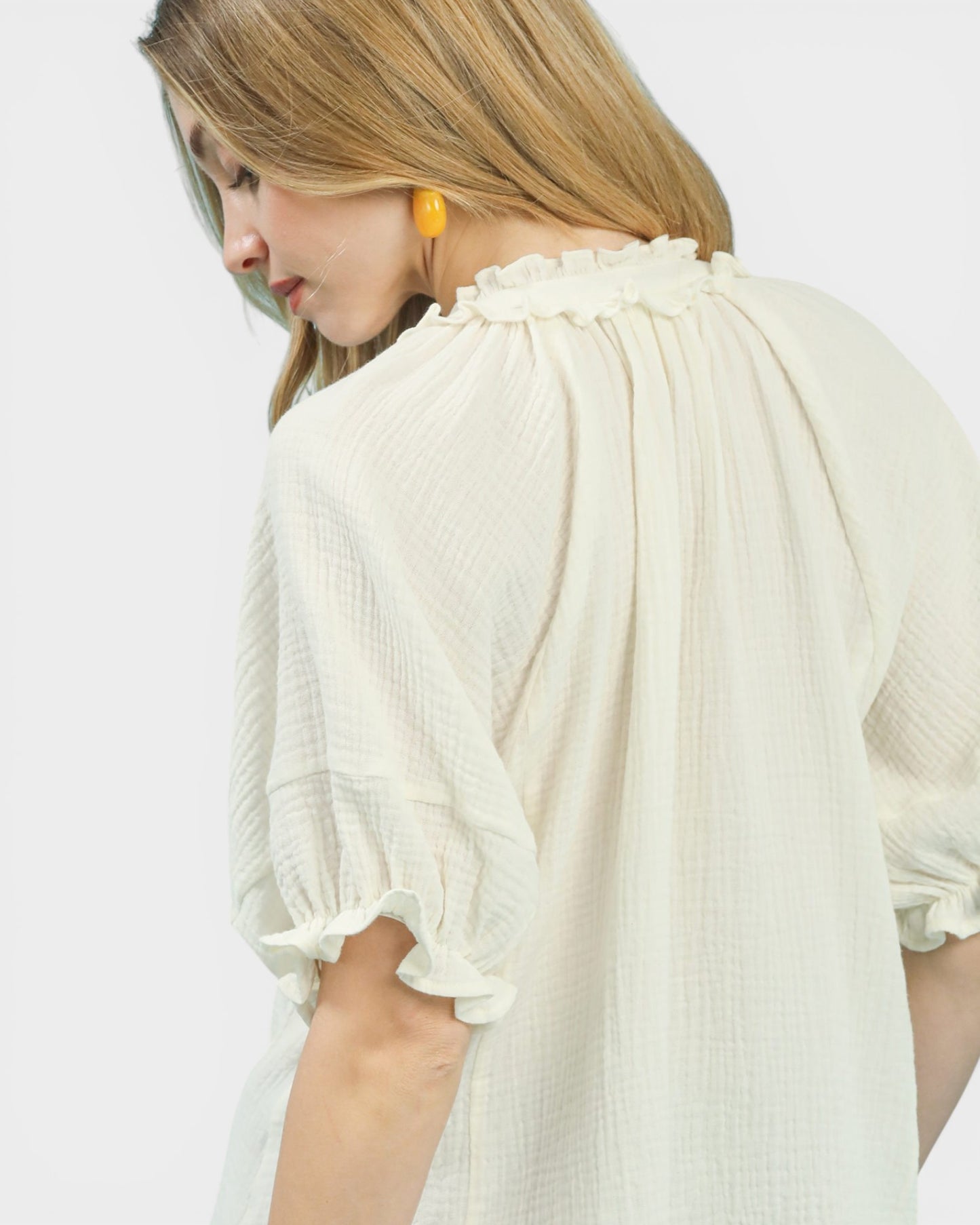 Woman wearing a white blouse with ruffled sleeves on a light background