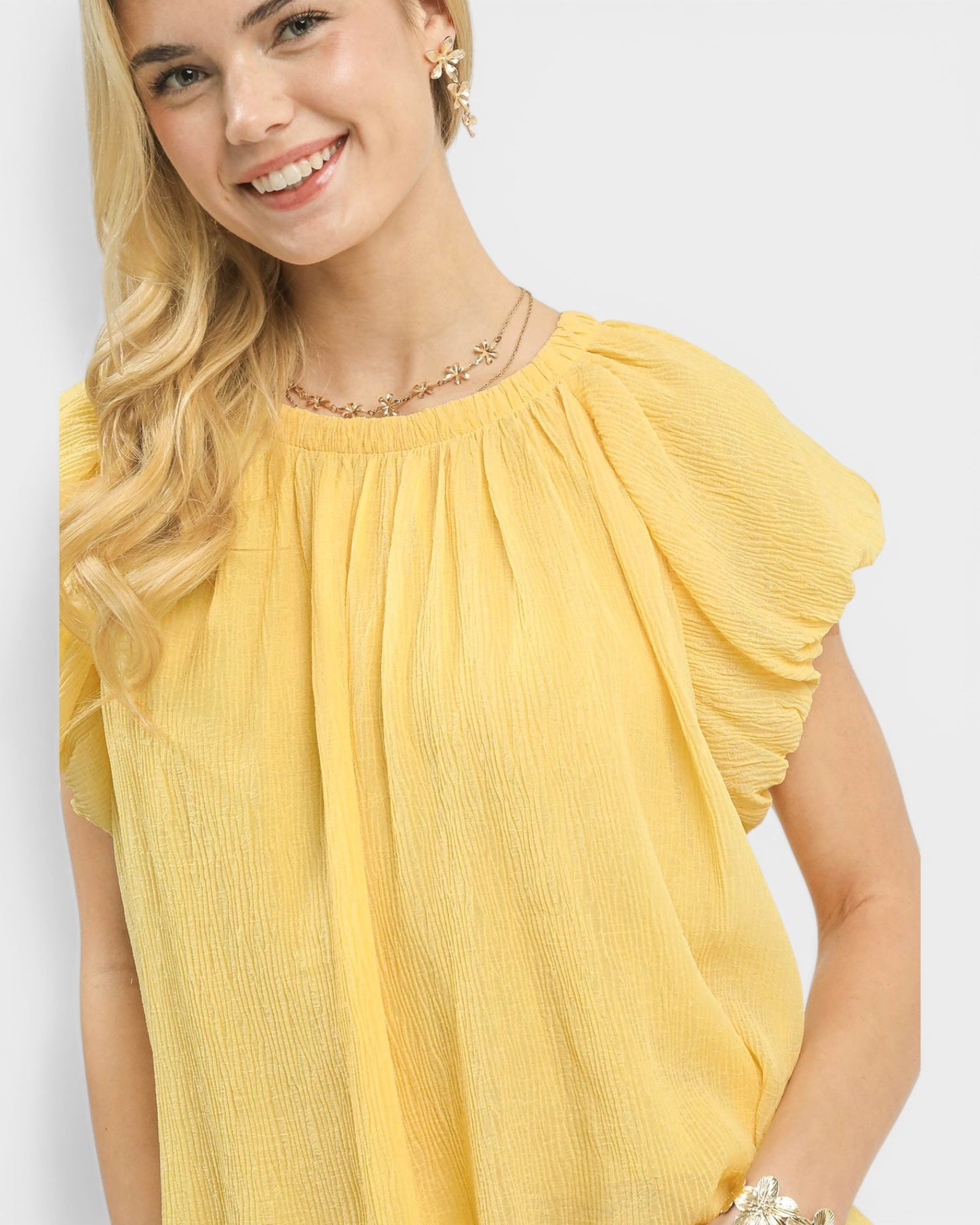 Woman wearing a yellow blouse with a plain background