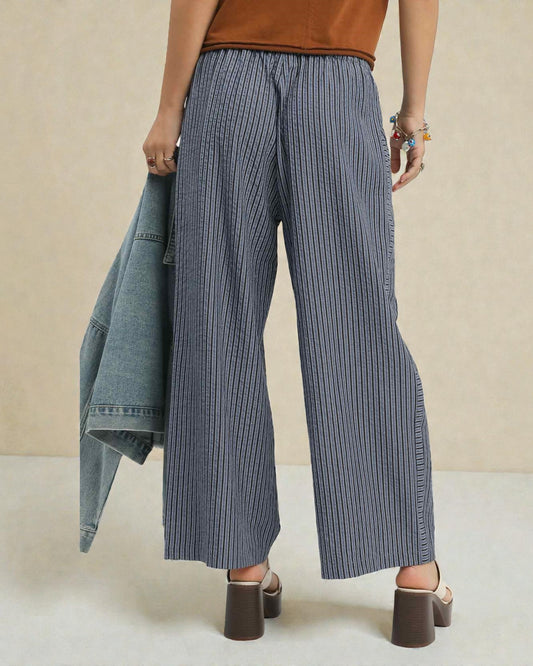 Person wearing blue striped wide-leg pants with a beige background