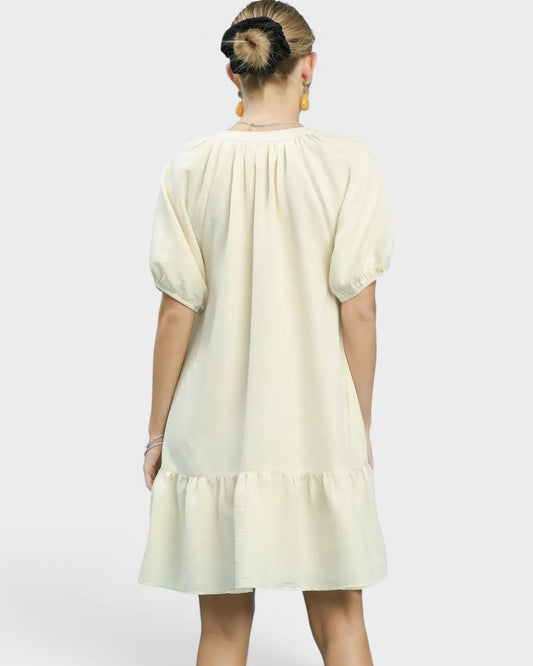 Person wearing a light-colored dress with a plain background