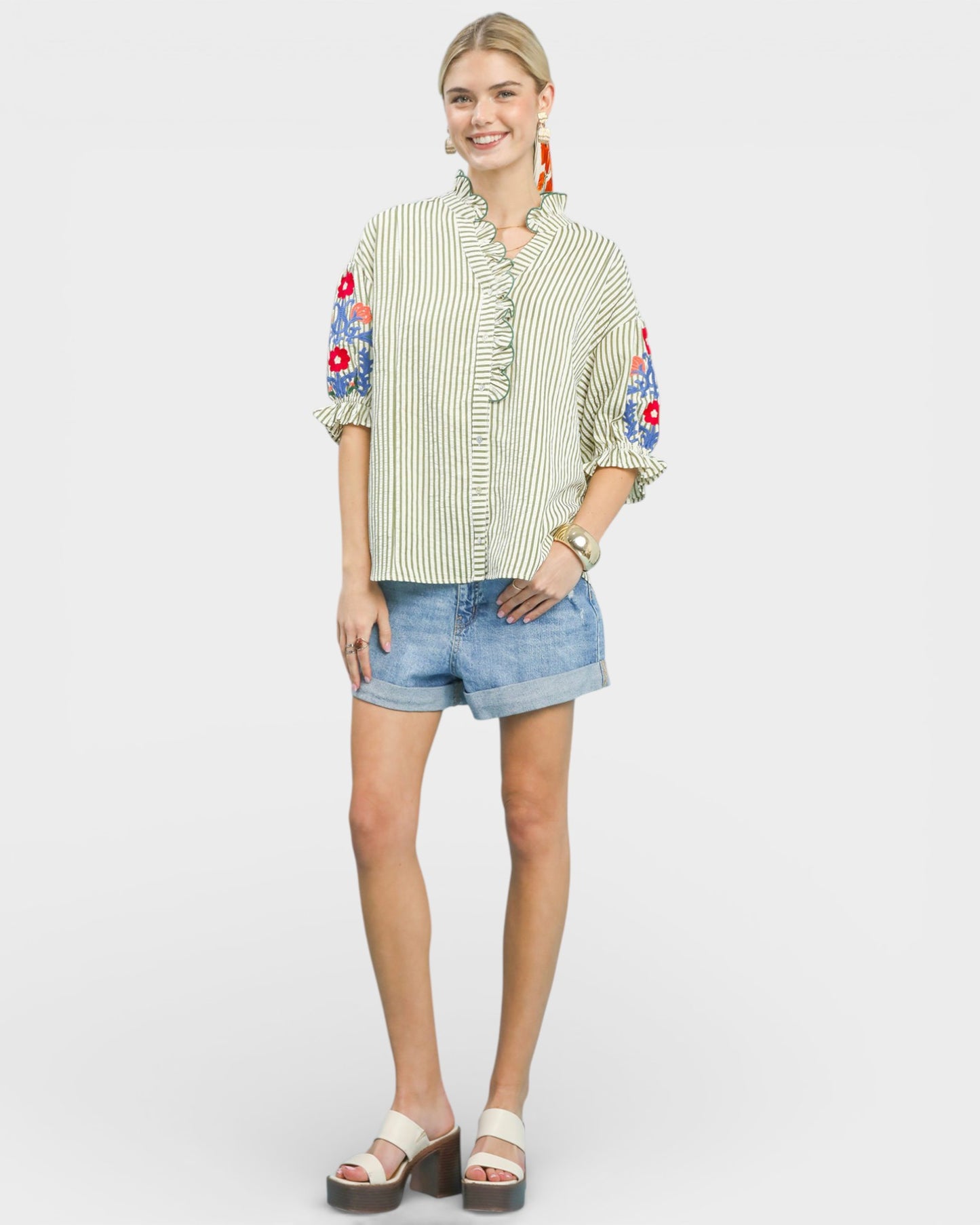 Woman wearing a striped shirt with floral sleeves and denim shorts on a white background