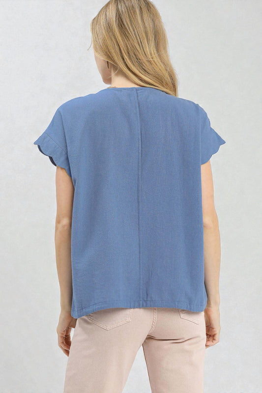 Woman wearing a blue sleeveless top and pink pants against a light gray background