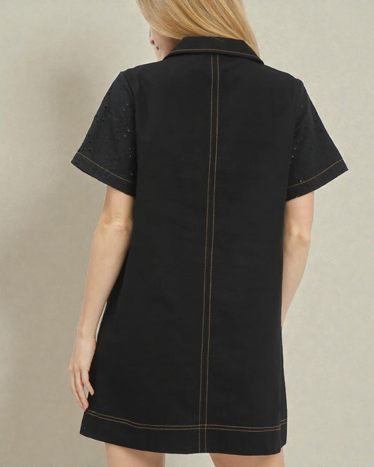 Black dress with white trim on a beige background