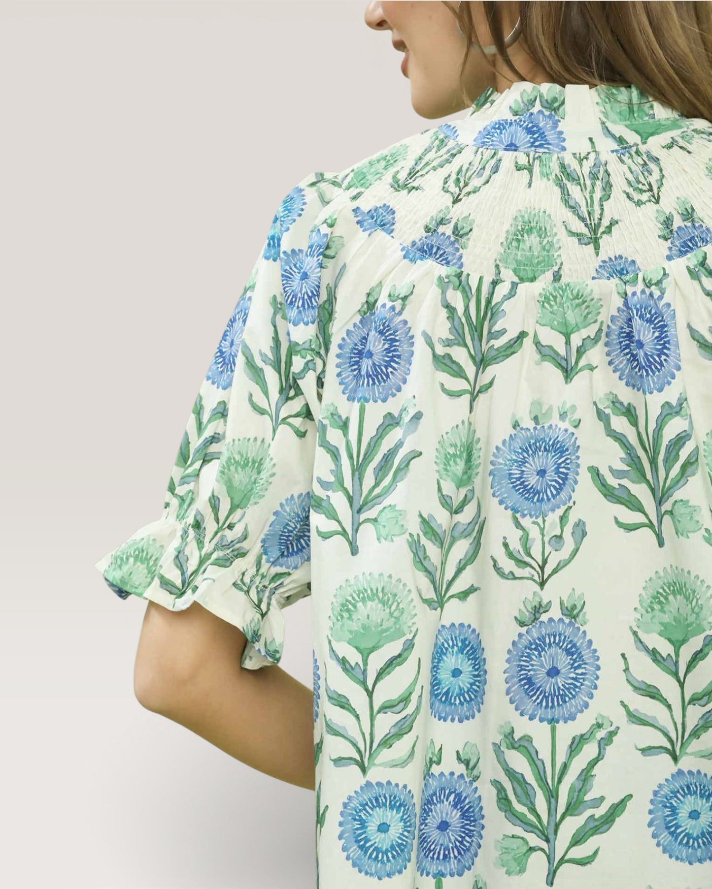 Woman wearing a floral blouse with blue and green flowers on a light background