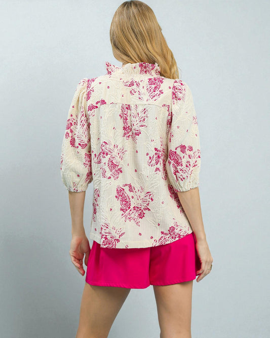 Woman wearing a floral blouse and pink shorts on a gray background