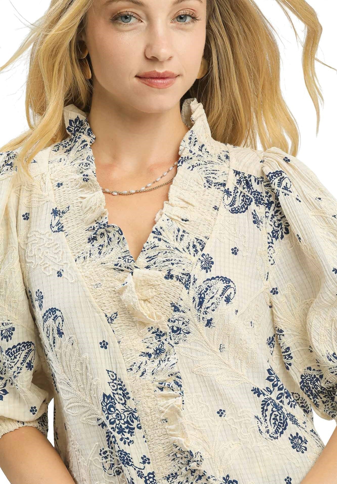 Woman wearing a white blouse with blue floral patterns on a white background