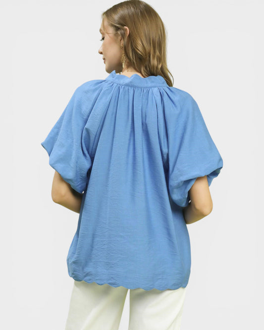 Person wearing a blue blouse with short sleeves on a white background