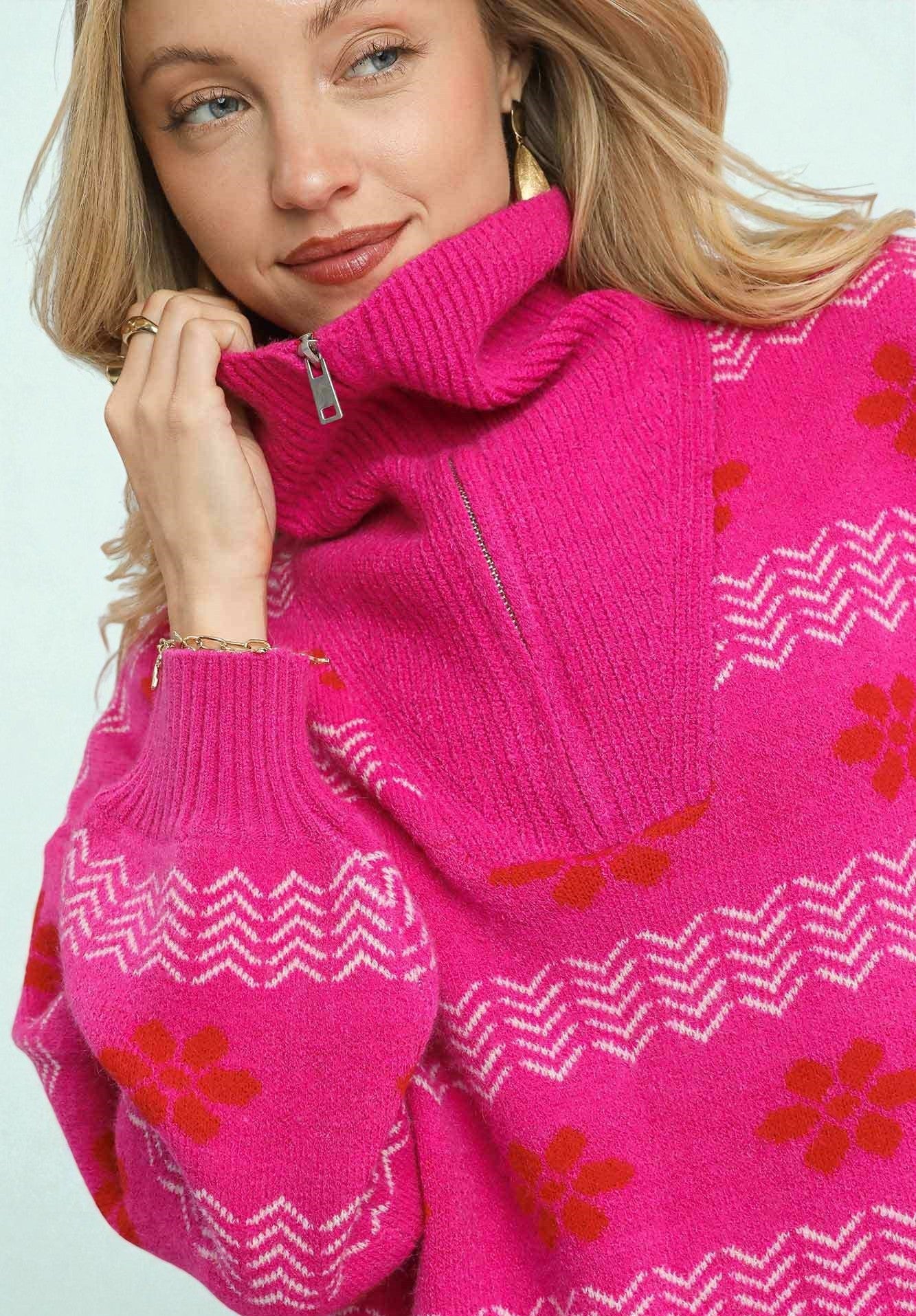 Woman wearing a bright pink sweater with floral patterns on a light blue background