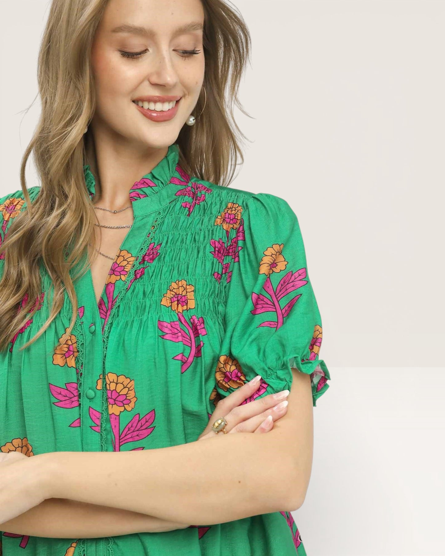 Woman wearing a green blouse with floral embroidery on a plain background