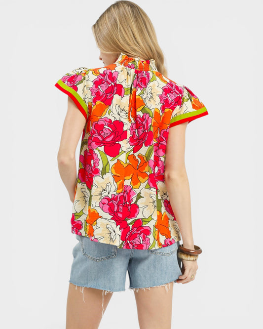 Person wearing a colorful floral shirt and denim shorts on a white background