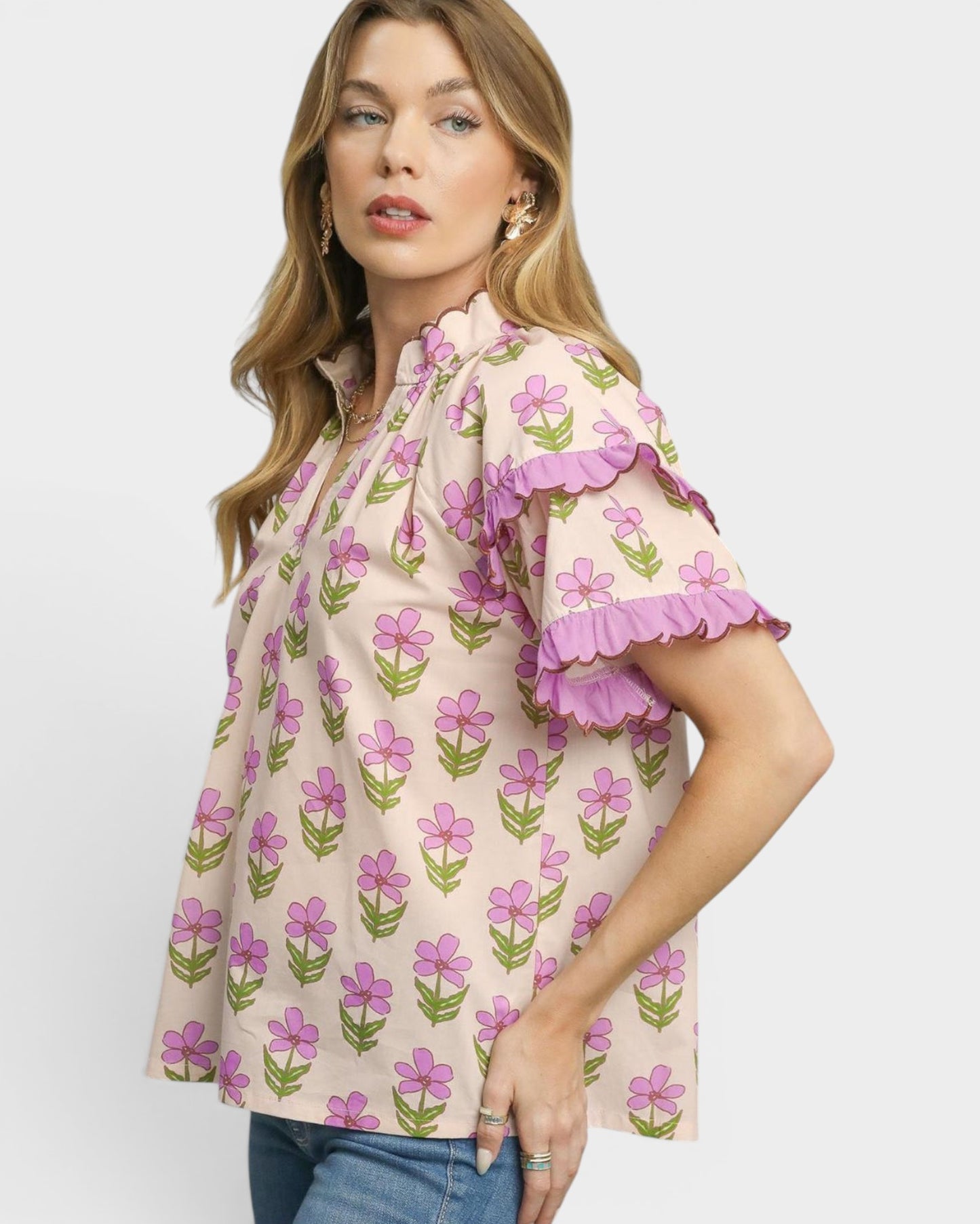 Woman wearing a floral blouse with ruffled sleeves on a plain background