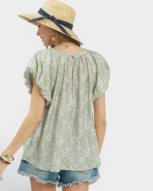 Woman wearing a floral blouse and straw hat with a blue ribbon on a white background