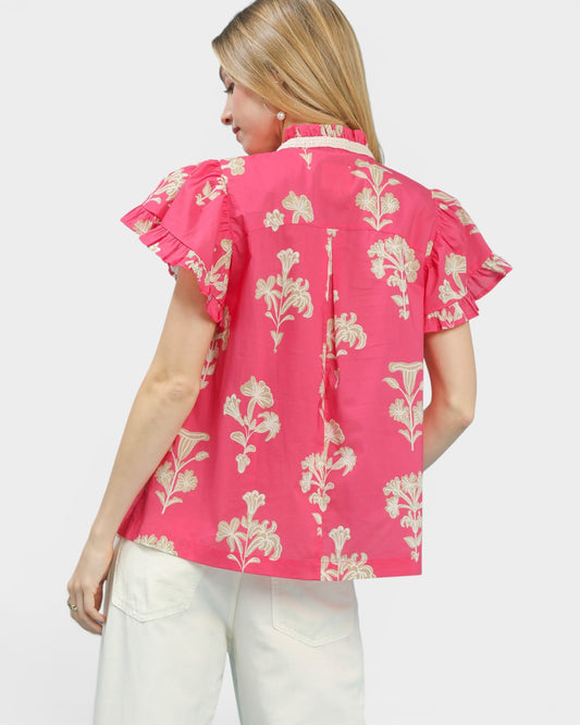 Woman wearing a pink floral blouse with ruffled sleeves on a white background