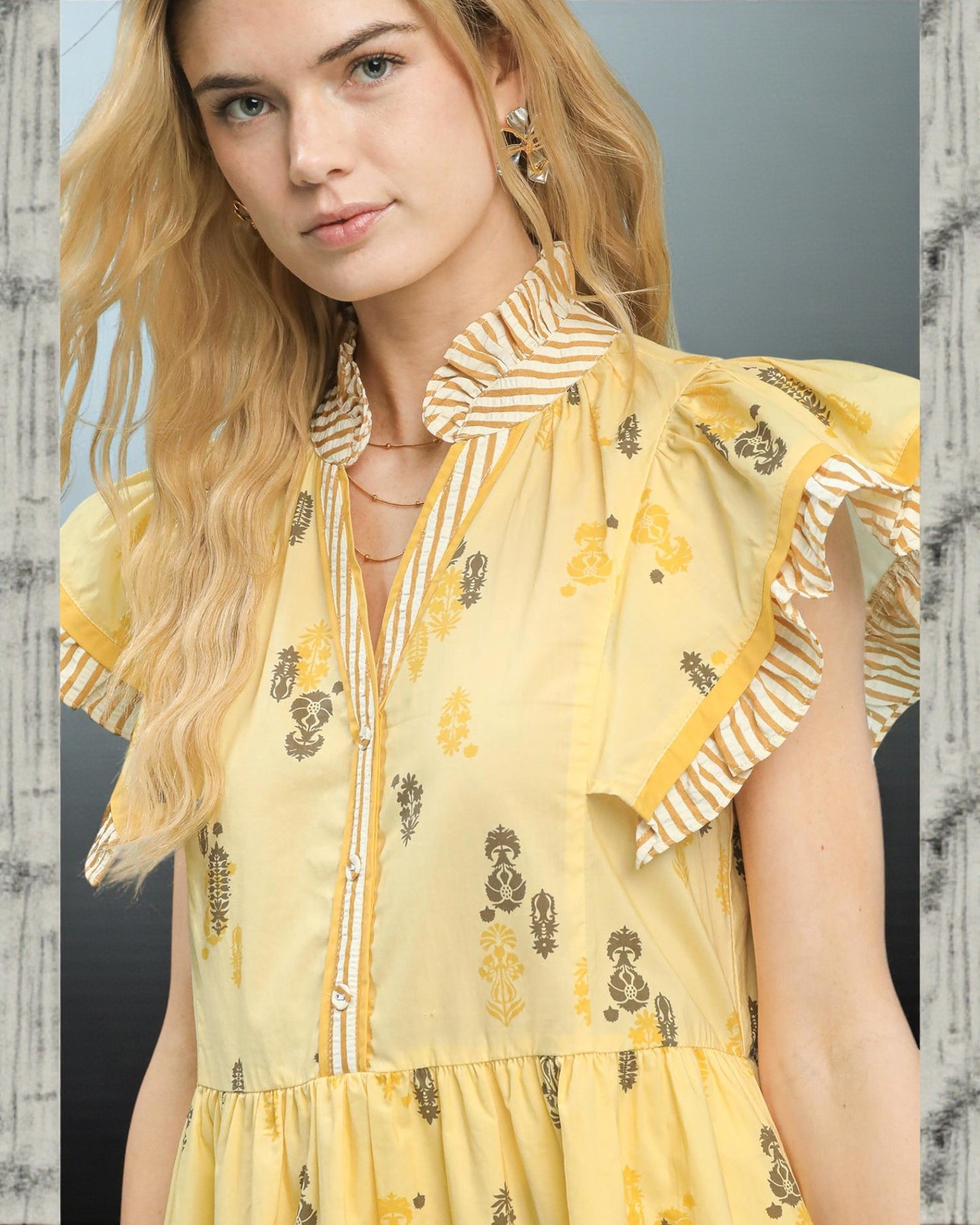 Woman wearing a yellow dress with floral patterns against a neutral background