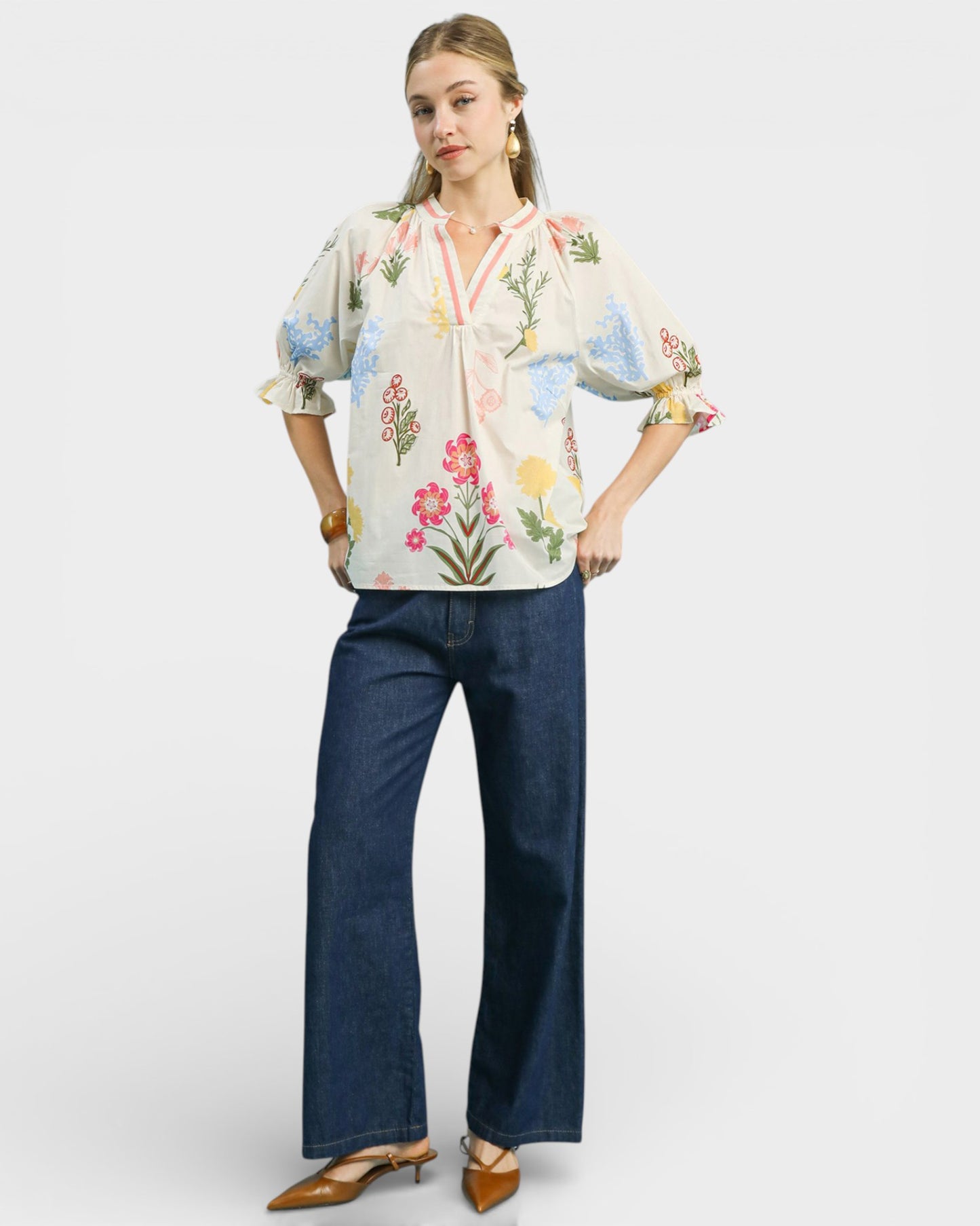 Woman wearing a floral blouse and blue jeans on a white background