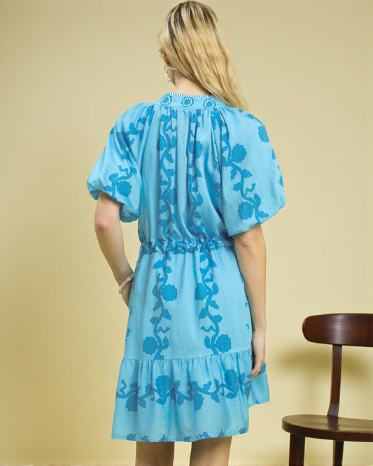 Woman wearing a blue floral dress against a beige background