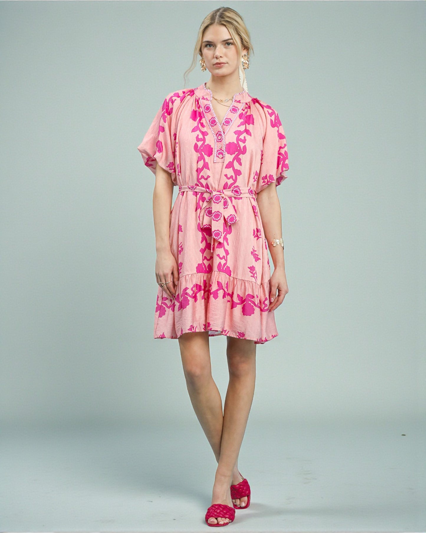 Woman wearing a pink floral dress on a gray background