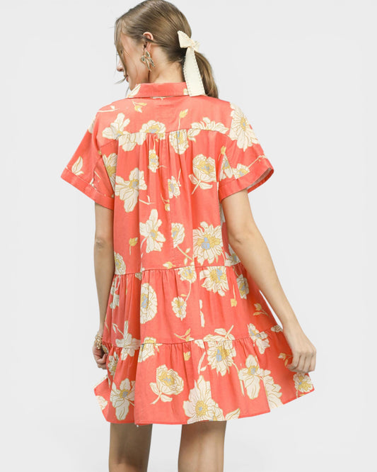 Woman wearing a coral floral dress on a white background