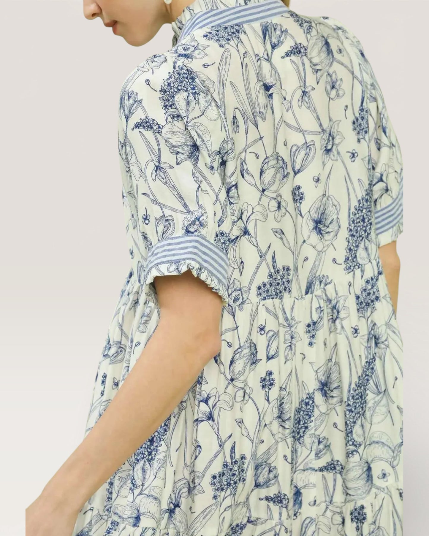 Person wearing a blue and white floral patterned dress on a plain background