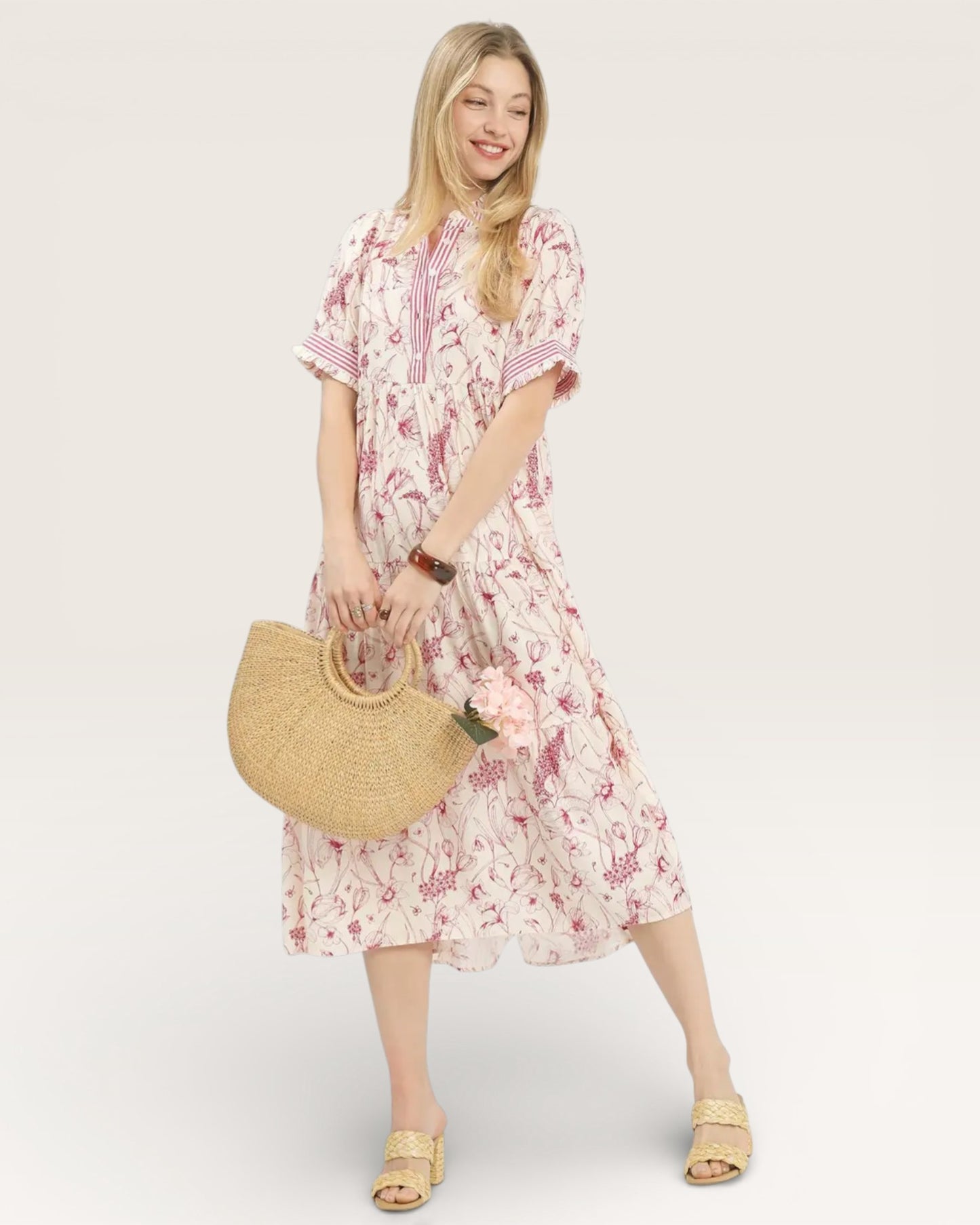 Woman wearing a floral dress holding a straw bag on a white background