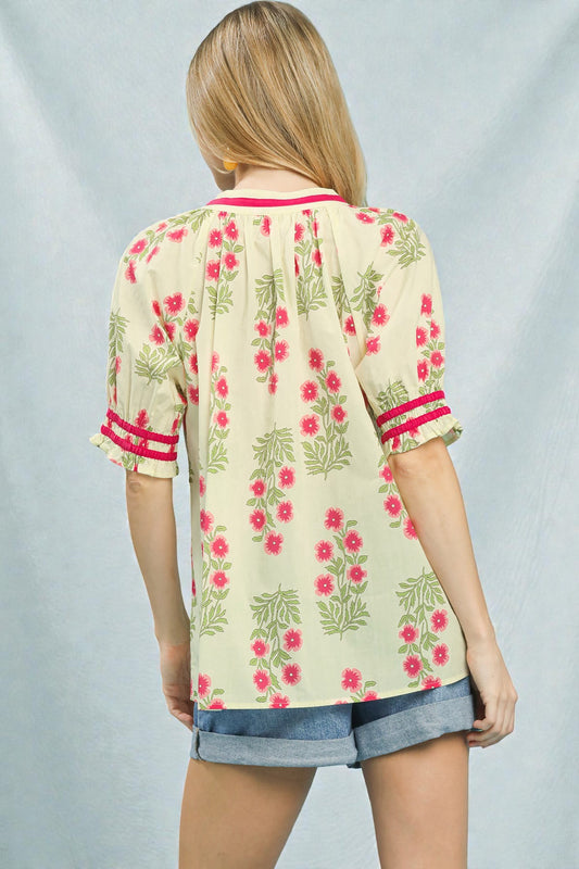 Woman wearing a floral blouse with red and green patterns on a plain background