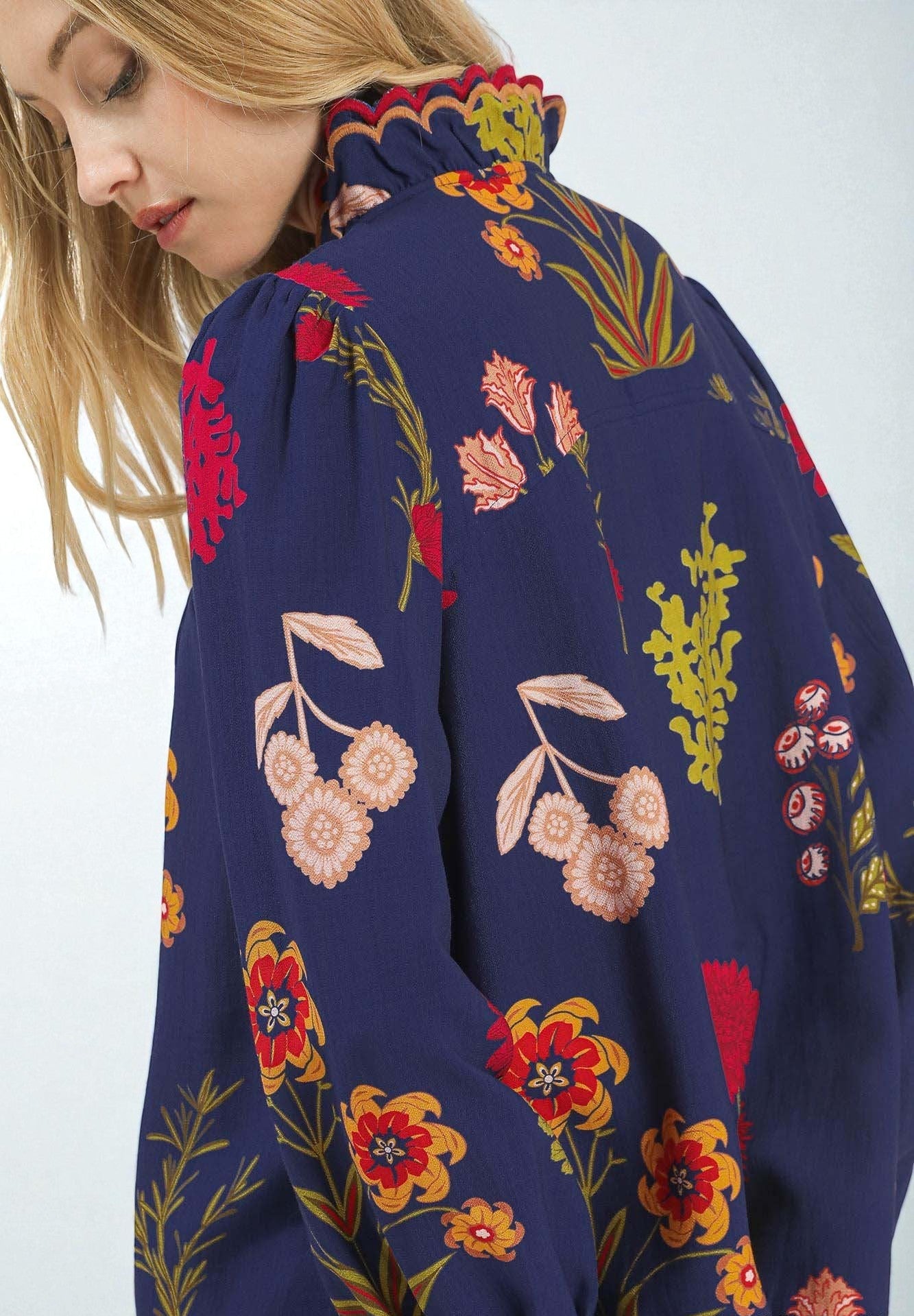 Navy blue dress with colorful floral pattern worn by a model on a white background