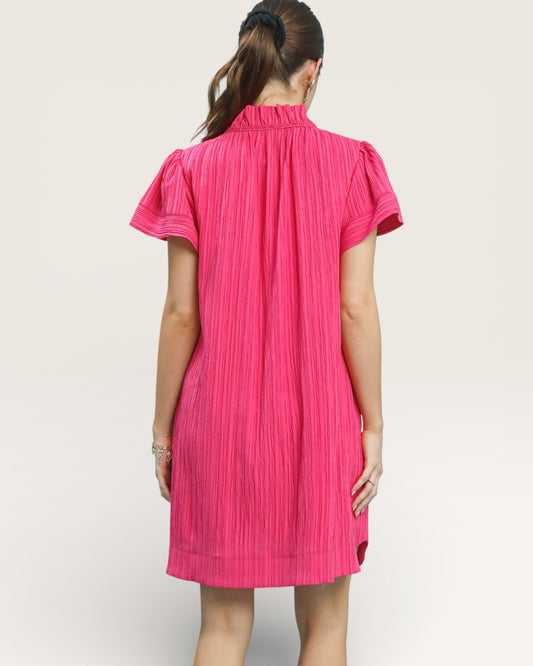 Person wearing a bright pink dress on a plain background